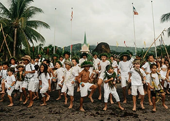 Children perform a traditional Tahitian welcome dance for Hōkūle‘a’s arrival in Papeʻetē, as featured on the Wa‘a Honua website.